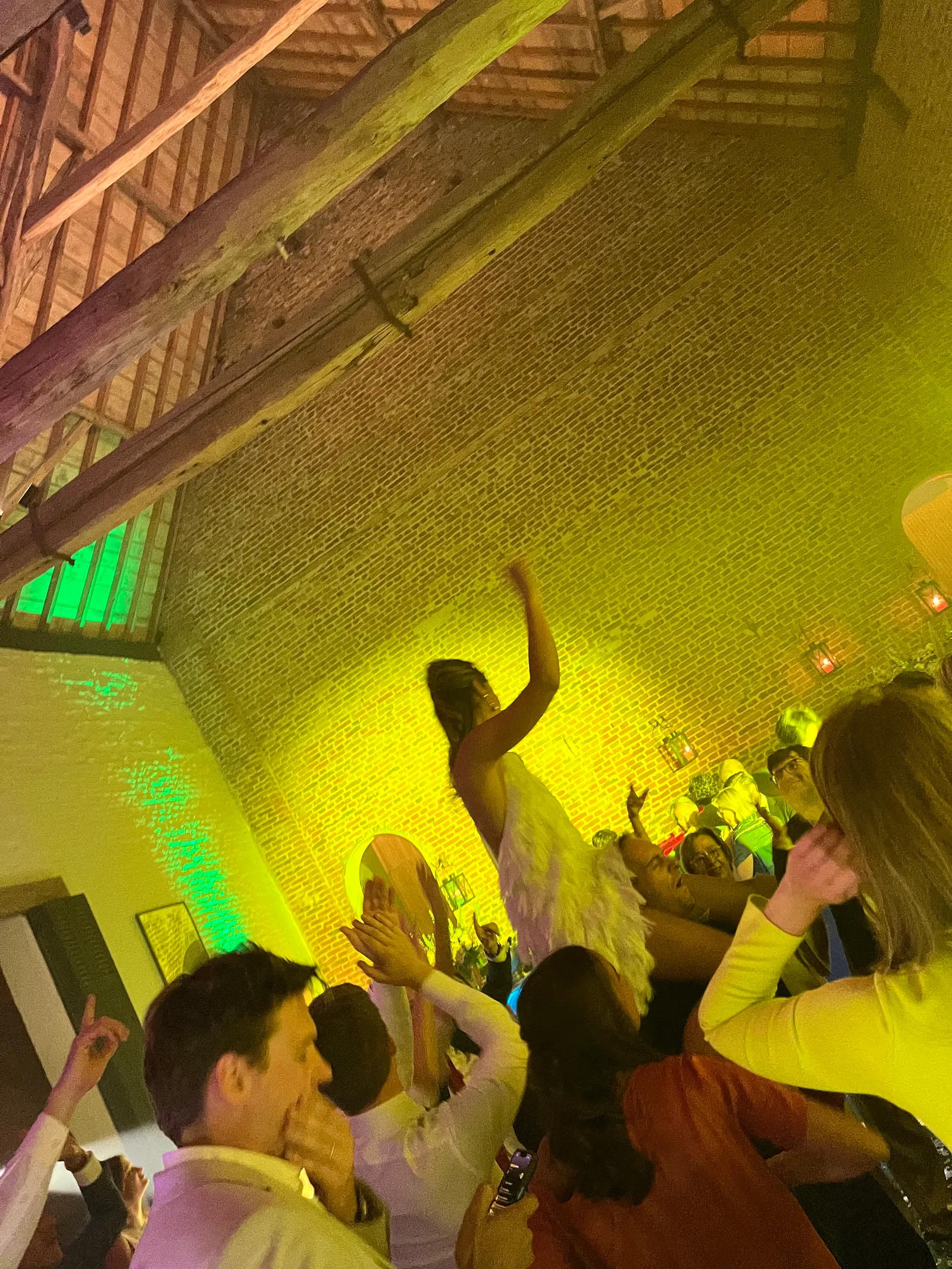 Dansvloer in geel licht, gasten met de handen in de lucht